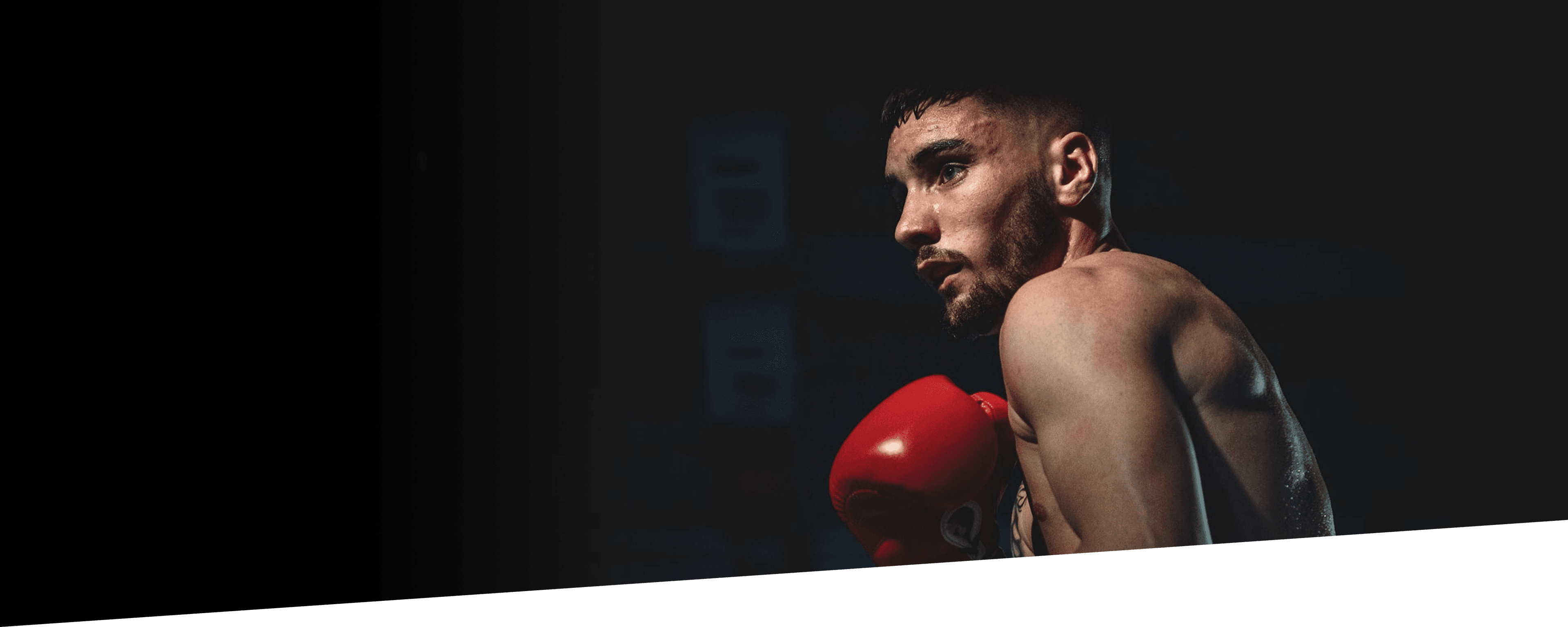Boxer wearing red gloves in a dark gym